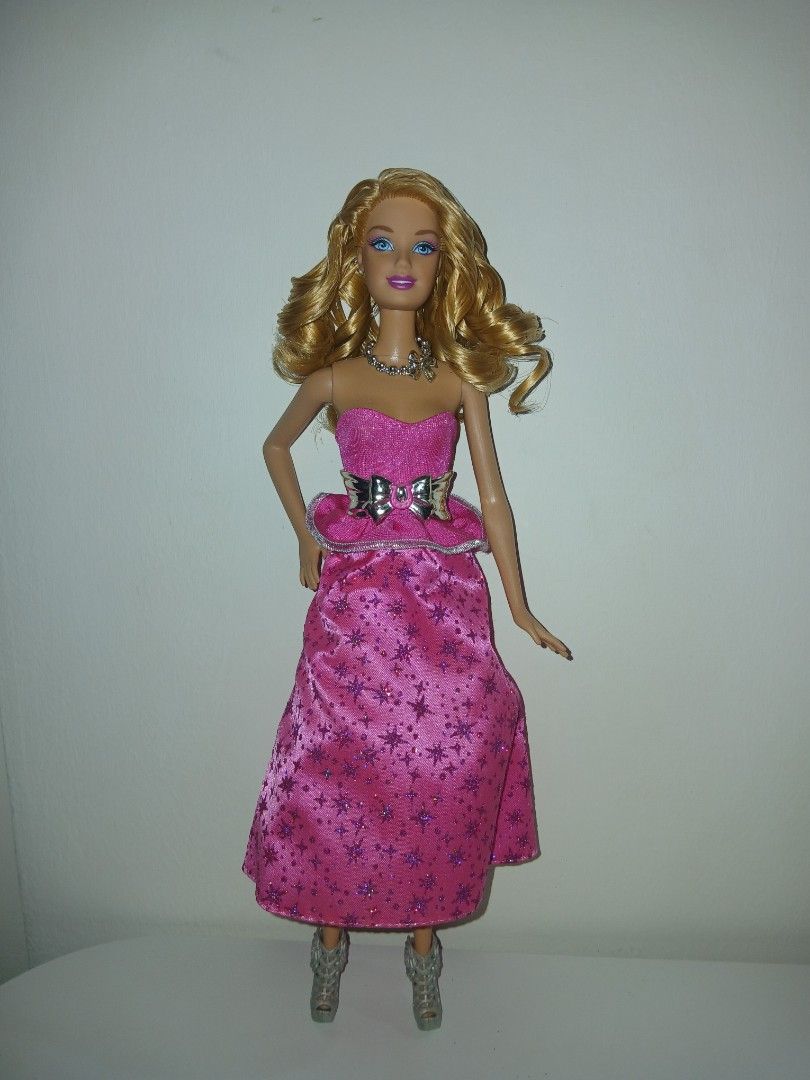 Barbie & her sisters pony tale 2013 (rare type) (Category: Kids Toys) located in Subic. Submitted by frncnjntmr22 (Listing ID 1467564290, Image 1). Description: - Doll details: Blonde hair with bouncy curls, striking blue eyes - Outfit: Vibrant pink strapless dress with purple star patterns - Accessories: Metallic silver beaded necklace and matching silver bow belt - Footwear: Matching silver high-heeled shoes - Condition: Clean and fully intact 