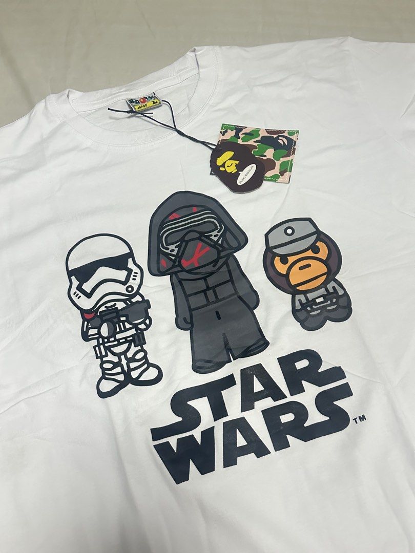 Bathing Ape x Star Wars Graphic Tee White Size L (Category: Tshirts & Polo Shirts ) located in Manila. Submitted by jmdrgooddeals (Listing ID 1467378681, Image 1). Description: - Brand: Bathing Ape x Star Wars Collaboration - Condition: Brand new with original store tags attached - Size: L (label inside collar) - Color: Clean white - Front Design: Stormtrooper, Kylo Ren, and Baby Milo graphic - Back Design: Grogu, The Mandalorian, and Star Wars l