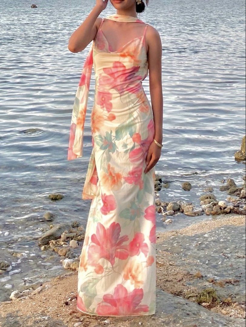 Beach Maxi Dress with Matching Scarf (Category: Dresses) located in Taguig. Submitted by seo_ari (Listing ID 1467378197, Image 1). Description: - Long floral maxi dress with vibrant pink, orange, and green flowers on a soft cream background - Chic cowl neckline with adjustable thin spaghetti straps - Trendy open-back design with hanging ties - Lightweight, floor-length fabric for effortless movement - Includes a matching free neck scarf to comple
