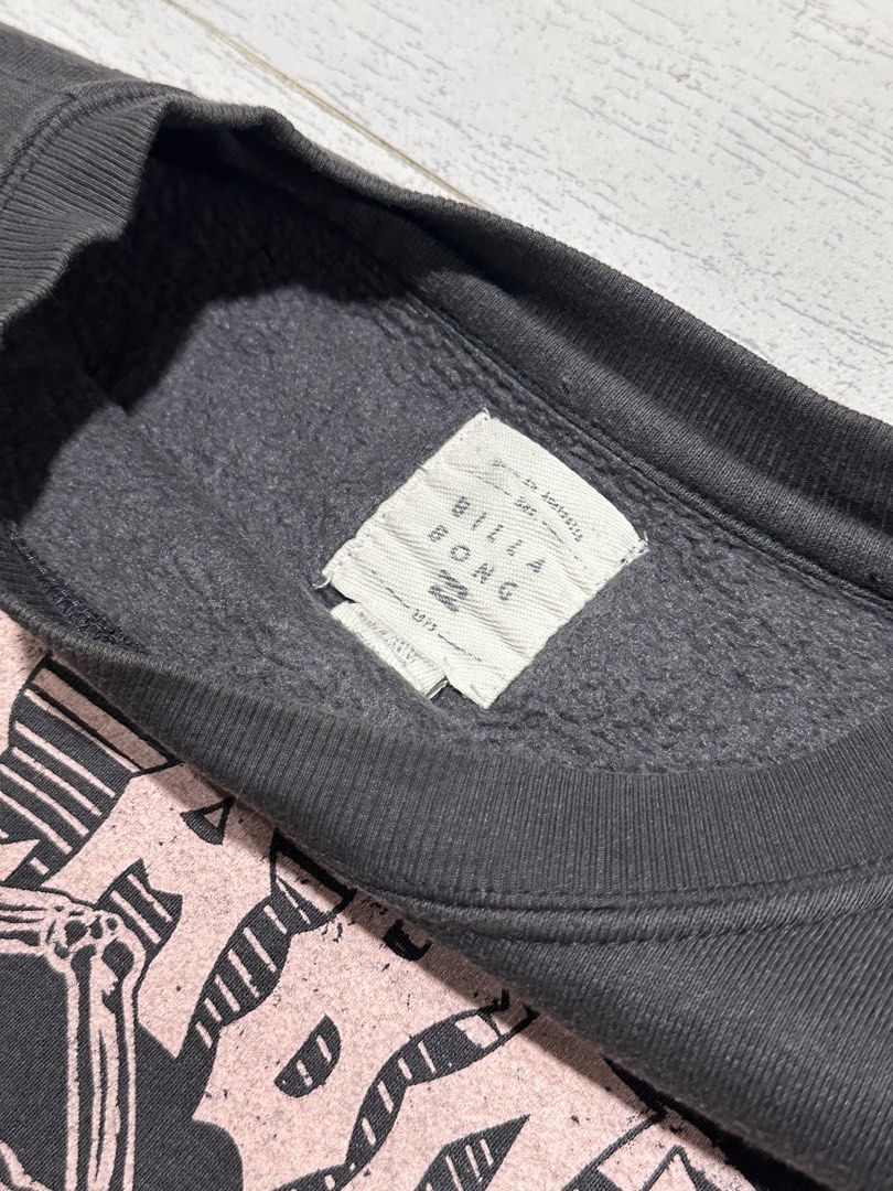 Billabong Let It Shine Skeleton Graphic Sweatshirt (Category: Coats, Jackets and Outerwear) located in La Trinidad. Submitted by christian_dutch (Listing ID 1467562667, Image 3). Description: - Brand: Billabong - Color: Dark grey with faded pink lettering - Size: Large (Standard fit) - Design: Large skeleton graphic on front with '1973' and 'Let It Shine' - Interior: Soft fleece lining for extra warmth and comfort - Details: Ribbed cuffs and hem 