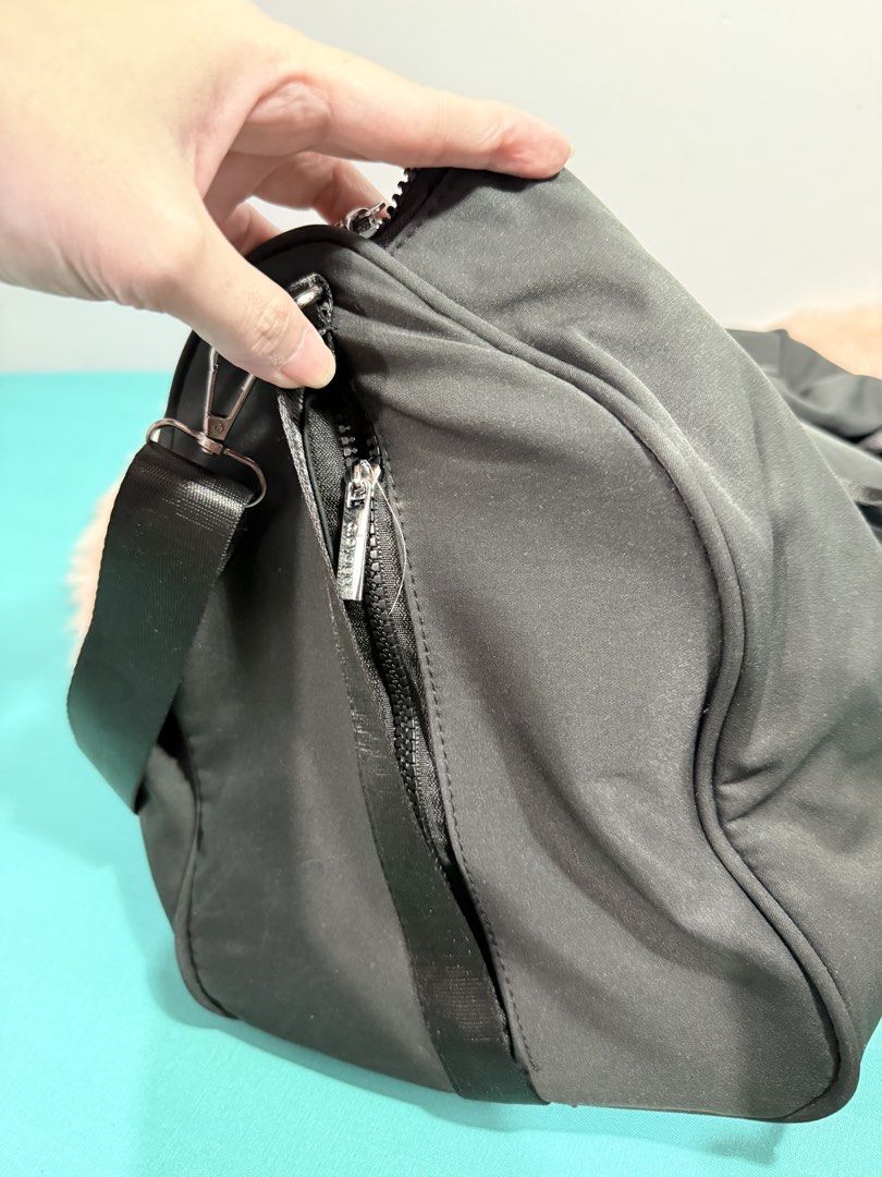 Black Duffle Bag Gym Bag (Category: Sling Bags) located in Quezon City. Submitted by shaberbree (Listing ID 1467521646, Image 3). Description: - Color: Black with prominent white logo print - Material: Durable high-quality nylon - Compartments: Wide dual-zipper main opening, side zipper compartment, and internal zip pocket - Interior: Branded "alo yoga" patterned fabric lining - Straps: Sturdy grab handles + removable/adjustable shoulder strap wi