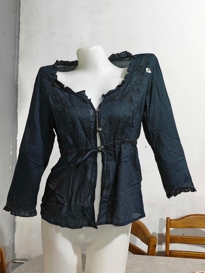 Black embroidered button-down blouse with tie waist (Category: Blouses) located in Quezon City. Submitted by cleocastillo_262 (Listing ID 1467382680, Image 1). Description: - Color: Dark green or black - Design: Button-down front with delicate floral embroidery on neckline and shoulders - Fit: Adjustable tie string at the waist - Details: Ruffle trim on collar and cuffs - Fabric: Lightweight, breathable, and textured material - Condition: Brand n