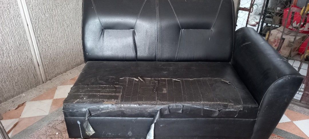 Black leatherette 2-seater sofa with armrest (Category: Sofas) located in Quezon City. Submitted by ki_cai (Listing ID 1467440083, Image 2). Description: - Type: 2-seater faux leather sofa with right-side armrest - Color: Classic black - Condition: Significant wear, tears, and tape repairs on the seat cushion - Best for: Reupholstering, recycling projects, or casual garage/workshop seating area: batasan hills q.c. .