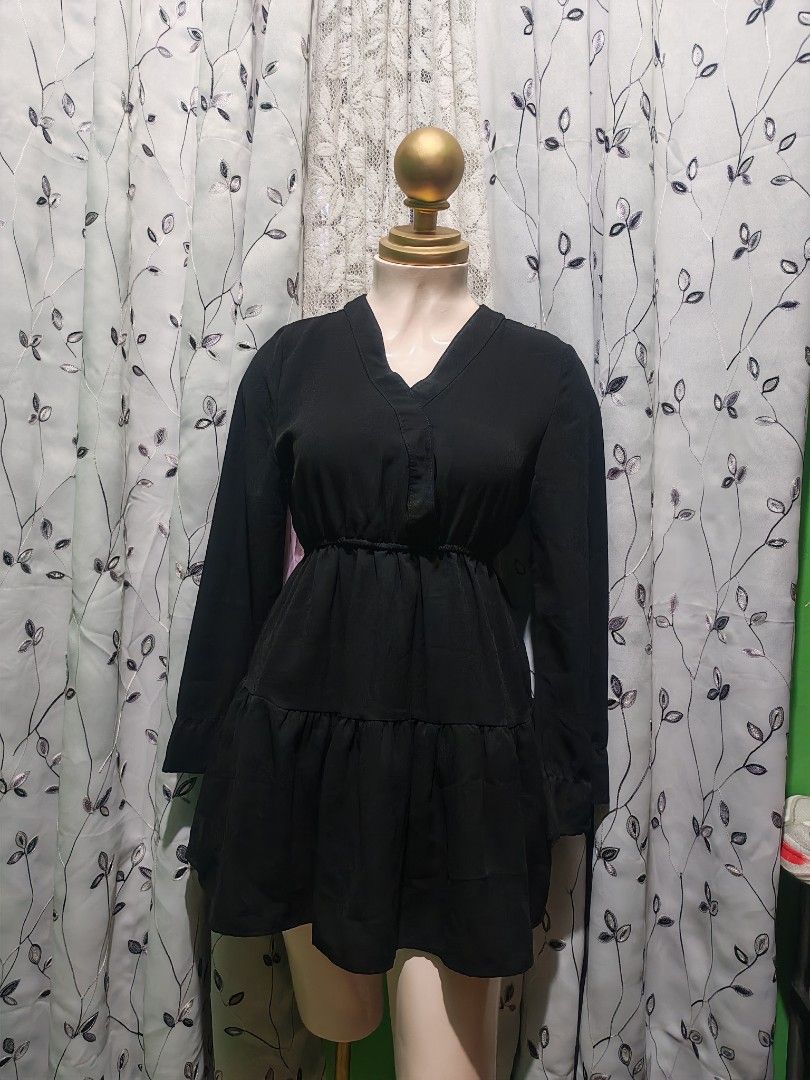 Black Long Sleeve Mini Dress (Category: Dresses) located in Caloocan City. Submitted by _misskaye (Listing ID 1467472781, Image 2). Description: - Color: Classic Black - Style: Long sleeve mini dress with V-neckline and folded collar detail - Fit: Elastic waistband for a comfortable, fitted silhouette - Design: Layered ruffled skirt portion for a chic look - Fabric: Smooth material throughout - Versatility: Easy to dress up with heels or style ca