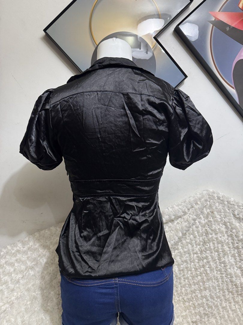 Black satin puff sleeve v-neck blouse (Category: Blouses) located in Marikina City. Submitted by lorradel (Listing ID 1467514924, Image 3). Description: - Color: Black - Material: Soft, lightweight, and shiny satin fabric - Design: Deep V-neck collar with short puff sleeves - Fit: Empire waist with gathered pleats below the bust and two front button accents - Styling: Perfect for dressing up with jeans or a skirt - MAY HAVE some washable stains (