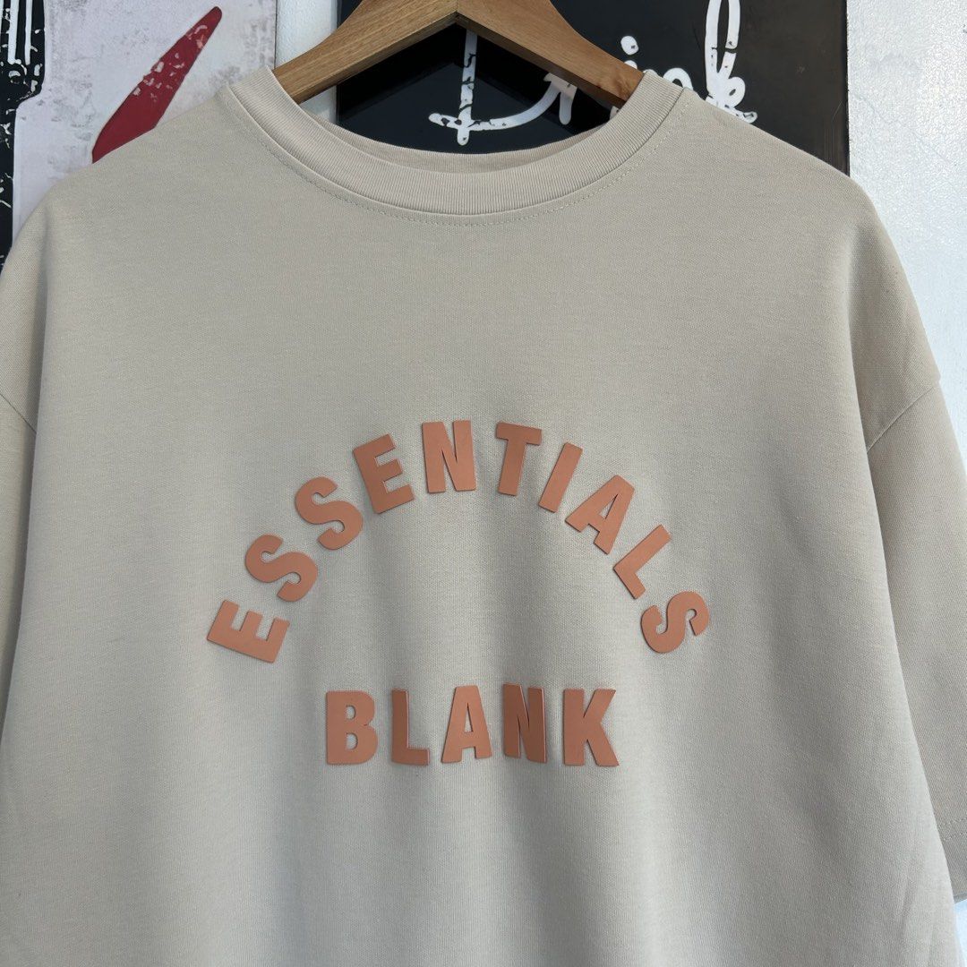 Blank Essentials Beige T-Shirt Size M (Category: Shirts) located in Manila. Submitted by jakes_thrift_shop (Listing ID 1467509791, Image 2). Description: - Brand: Blank Essentials - Color: Beige - Size: M - Material: 60% cotton, 40% polyester - Design: Raised orange 'ESSENTIALS BLANK' lettering on the chest - Detail: Rubberized brand patch with Japanese text on the upper back - Fit: Relaxed fit with short sleeves and crew neck.