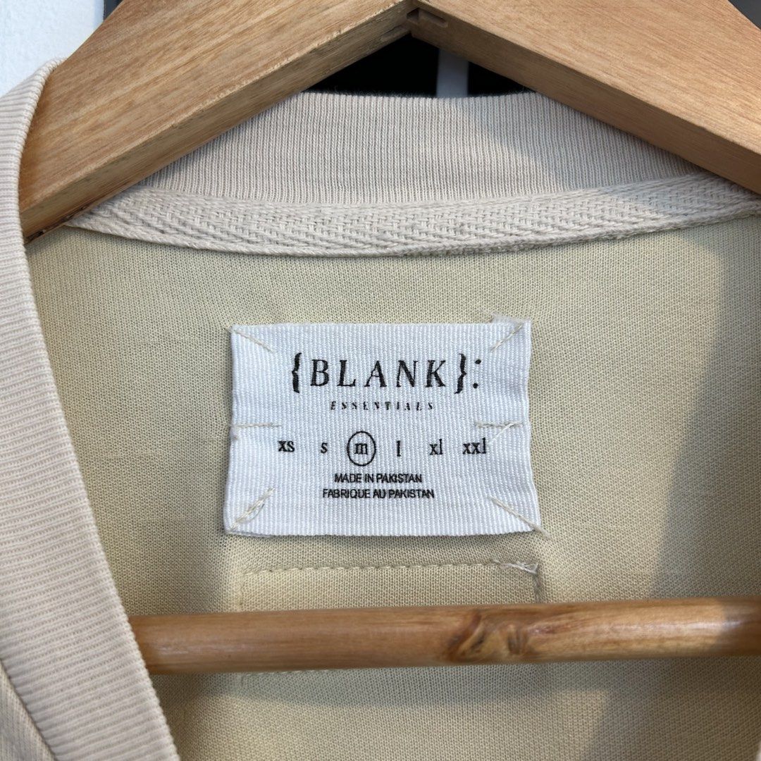 Blank Essentials Beige T-Shirt Size M (Category: Shirts) located in Manila. Submitted by jakes_thrift_shop (Listing ID 1467509791, Image 3). Description: - Brand: Blank Essentials - Color: Beige - Size: M - Material: 60% cotton, 40% polyester - Design: Raised orange 'ESSENTIALS BLANK' lettering on the chest - Detail: Rubberized brand patch with Japanese text on the upper back - Fit: Relaxed fit with short sleeves and crew neck.