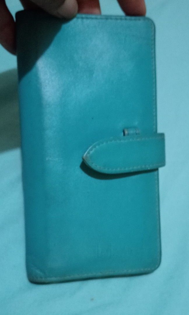 Blue leather wallet with multiple card slots (Category: Wallets & Card holders) located in Makati City. Submitted by YSL80022 (Listing ID 1467285415, Image 1). Description: - Color: Teal blue - Material: Genuine Leather - Features: Multiple 14 card slots, main cash compartment, and side strap with snap button closure - Condition: Pre-loved with some visible wear and tear on the inner lining and cardholder fabric - Status: Cleaned out from closet,