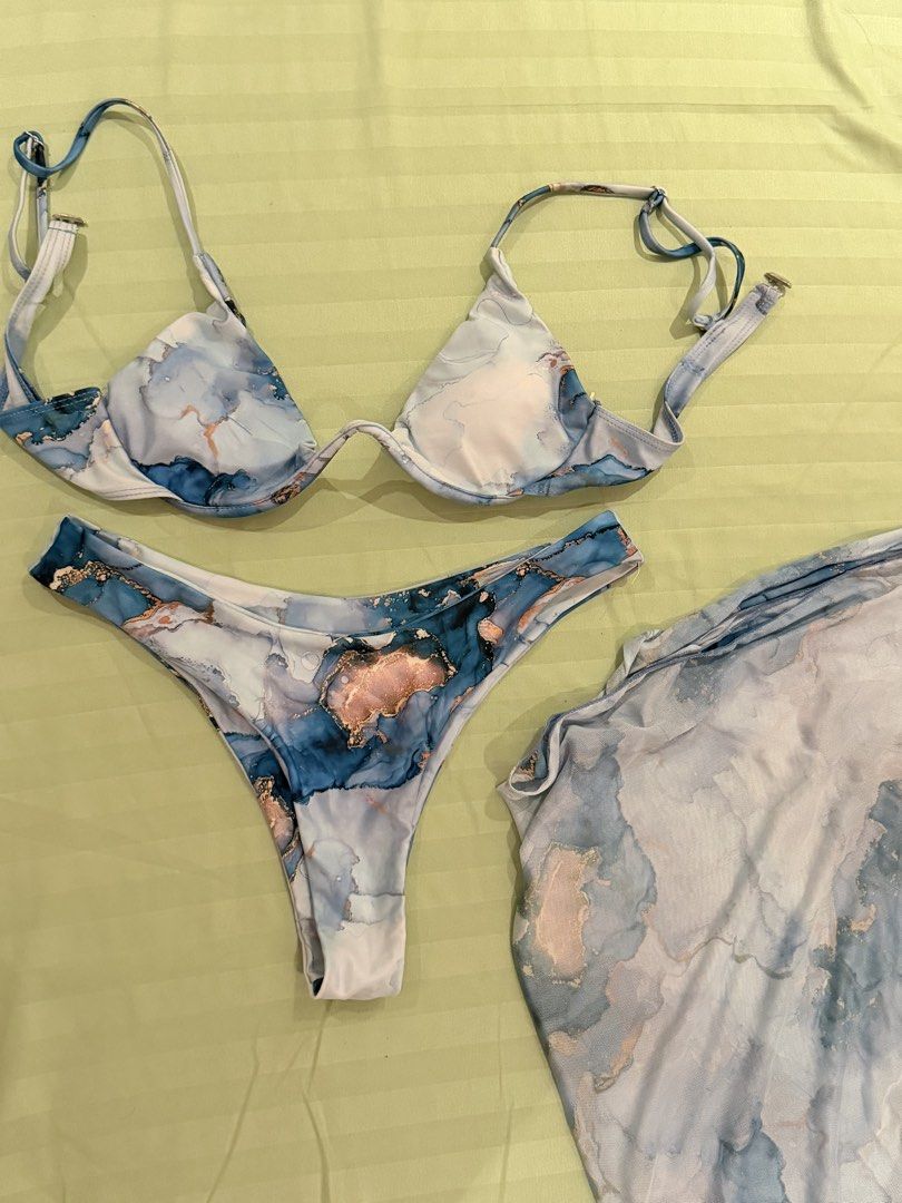 Blue Marble Print Bikini Set with Matching Sarong (Category: Bikinis & Swimsuits) located in Quezon City. Submitted by caathhx_ (Listing ID 1467511006, Image 1). Description: - Style: Matching 3-piece swim set (Underwire bikini top, high-cut bottoms, sheer wrap sarong) - Design: Blue and white abstract marble pattern with rose gold metallic foil accents - Fit: Adjustable straps on top - Condition: Brand new, never worn (tags removed).