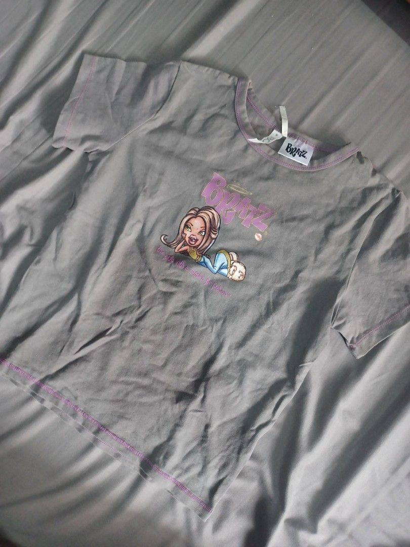 Bratz Grey Graphic Tee Size M (Category: Shirts) located in Manila. Submitted by quishi061210 (Listing ID 1467429599, Image 1). Description: - Color: Grey with purple contrast stitching - Size: M (tag attached) - Design: Cute Bratz character graphic on the chest - Material: Soft, comfortable cotton - Style: Y2K aesthetic, versatile for casual daily fits - Condition: Brand new with tags.