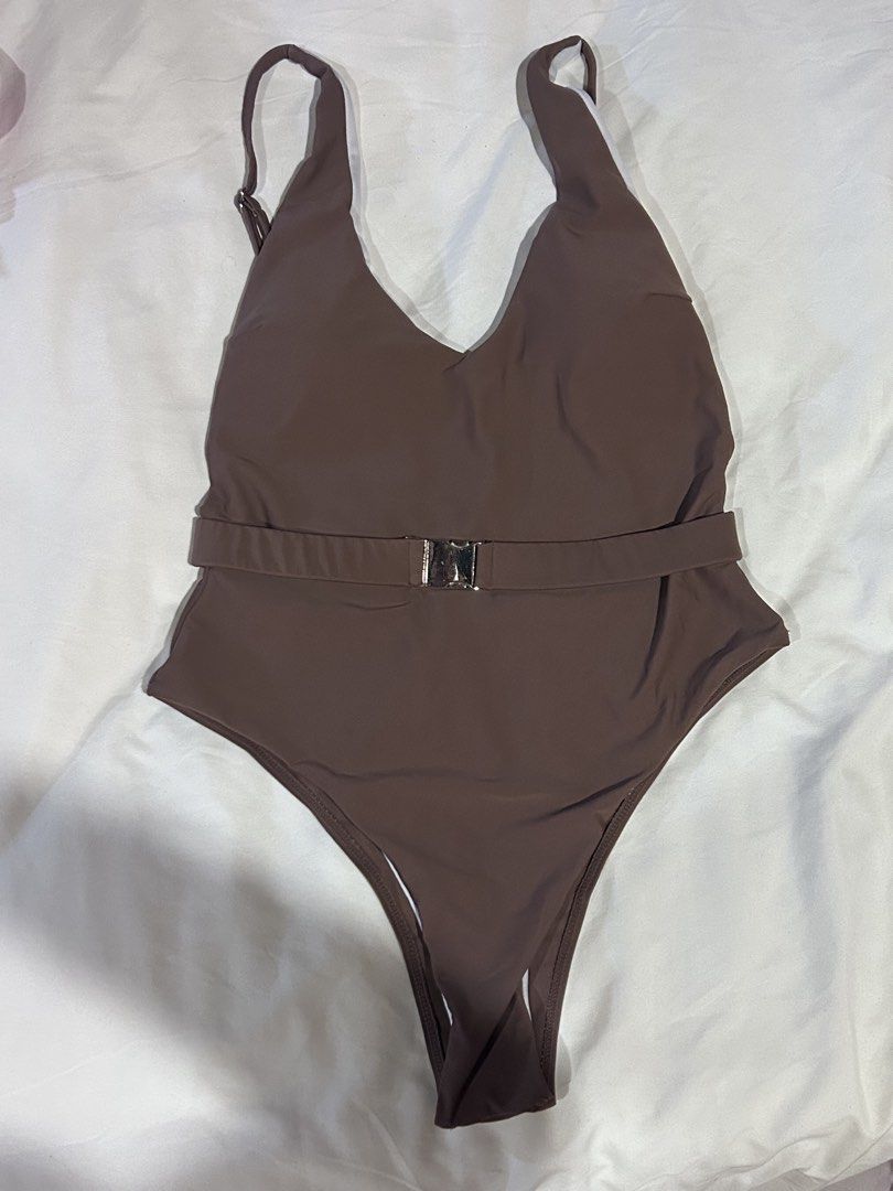 Brown One-Piece Swimsuit with Belt (Category: Bikinis & Swimsuits) located in Cebu City. Submitted by shopmikascloset (Listing ID 1467370739, Image 1). Description: - Color: Brown with white inner lining - Neckline: Deep V-neck on front and back - Straps: Adjustable with metal sliders - Details: Matching fabric waist belt with silver metallic buckle - Padding: Includes removable padding inserts - Fit: High-cut leg design.