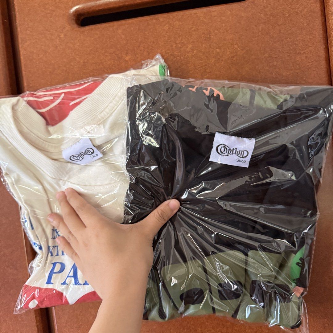 Bundle Thailand Graphic Tees (Category: Tshirts & Polo Shirts ) located in Davao. Submitted by keirousel (Listing ID 1467385803, Image 1). Description: - Brand: Option Shop - Quantity: 2-piece graphic tee bundle - White Tee: Features a bold, rice sack-inspired rose graphic on the front - Black Tee: Features large colorful lettering and round badge details - Condition/Details: Brand tags intact inside collar - Perfect for effortless streetwear sty