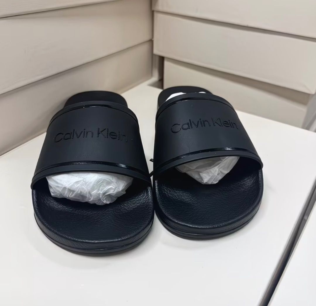 Calvin Klein Black Slide Sandals (Category: Flats & Sandals) located in Pasay City. Submitted by kgemsluxuryboutique (Listing ID 1467377422, Image 3). Description: - Brand: Calvin Klein - Color: Classic Black - Style: Slip-on slide sandals - Condition: Clean, like-new with original toe band paper stuffing - Features: Wide top strap with debossed logo lettering, textured footbed for extra grip - Best for: Lightweight, everyday casual wear Sizes 36