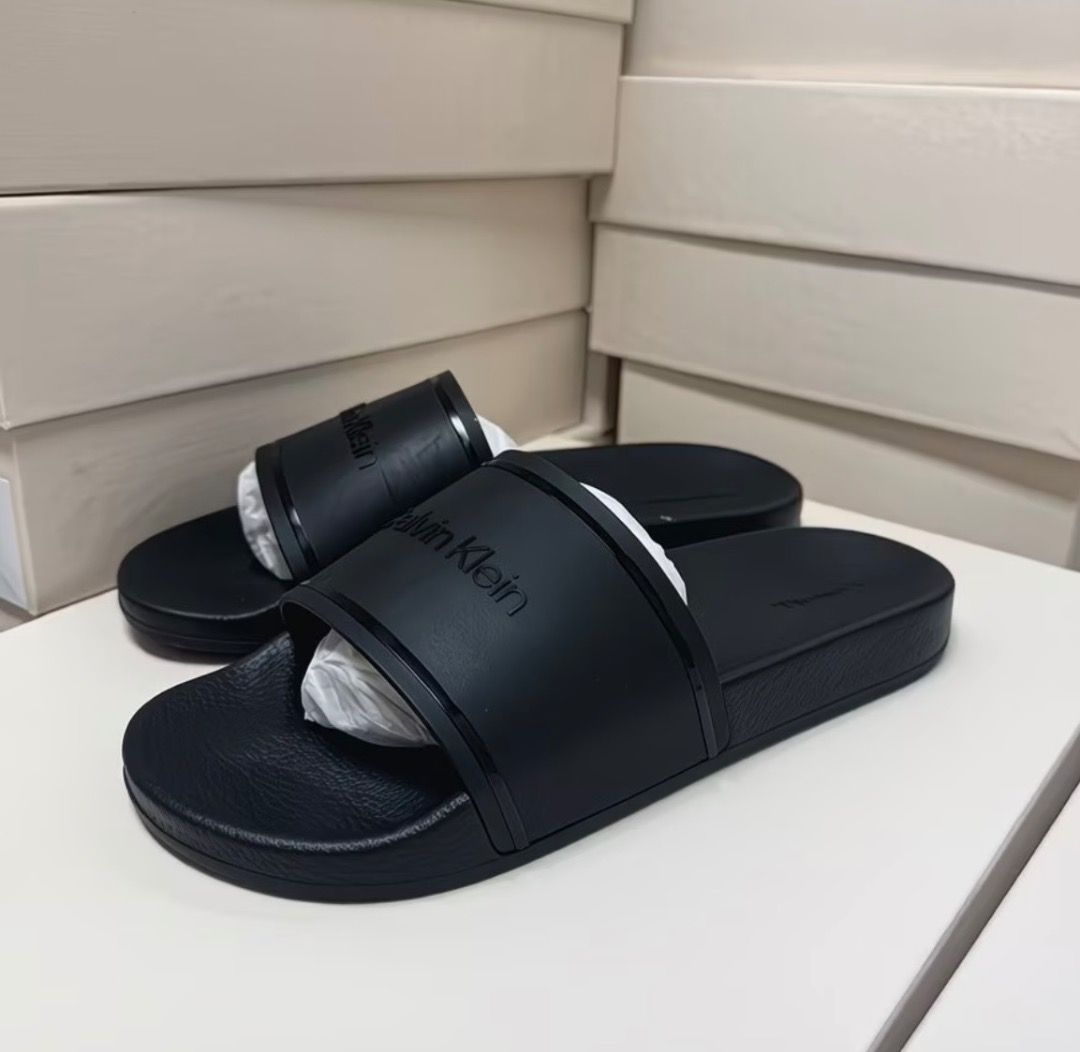 Calvin Klein Black Slide Sandals (Category: Flats & Sandals) located in Pasay City. Submitted by kgemsluxuryboutique (Listing ID 1467377422, Image 1). Description: - Brand: Calvin Klein - Color: Classic Black - Style: Slip-on slide sandals - Condition: Clean, like-new with original toe band paper stuffing - Features: Wide top strap with debossed logo lettering, textured footbed for extra grip - Best for: Lightweight, everyday casual wear Sizes 36