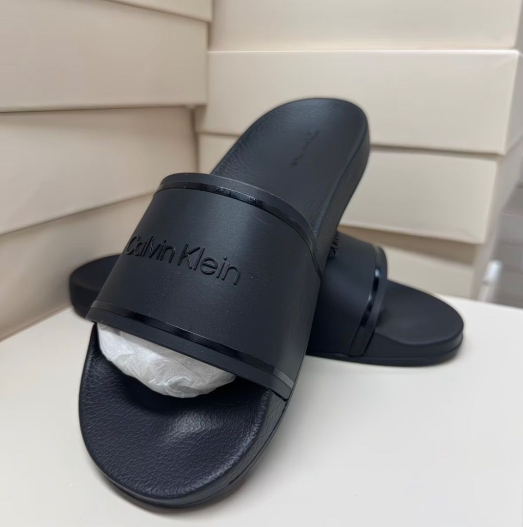 Calvin Klein Black Slide Sandals (Category: Flats & Sandals) located in Pasay City. Submitted by kgemsluxuryboutique (Listing ID 1467377422, Image 2). Description: - Brand: Calvin Klein - Color: Classic Black - Style: Slip-on slide sandals - Condition: Clean, like-new with original toe band paper stuffing - Features: Wide top strap with debossed logo lettering, textured footbed for extra grip - Best for: Lightweight, everyday casual wear Sizes 36
