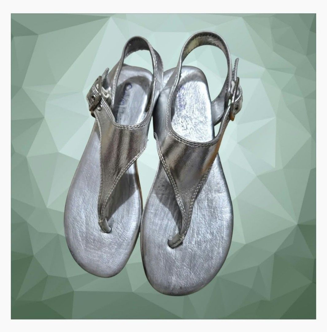 Calvin Klein Silver Thong Sandals (Moraca) (Category: Flats & Sandals) located in Paranaque City. Submitted by calm_youngstore7 (Listing ID 1467564644, Image 3). Description: Calvin Klein Moraca T-Strap Flat Sandals in a metallic silver colorway. Key Features • Design: Minimalist T-strap thong silhouette with a modern wide-set center panel. • Material: Crafted from a smooth, reflective metallic faux-leather upper with detailed perimeter stitching