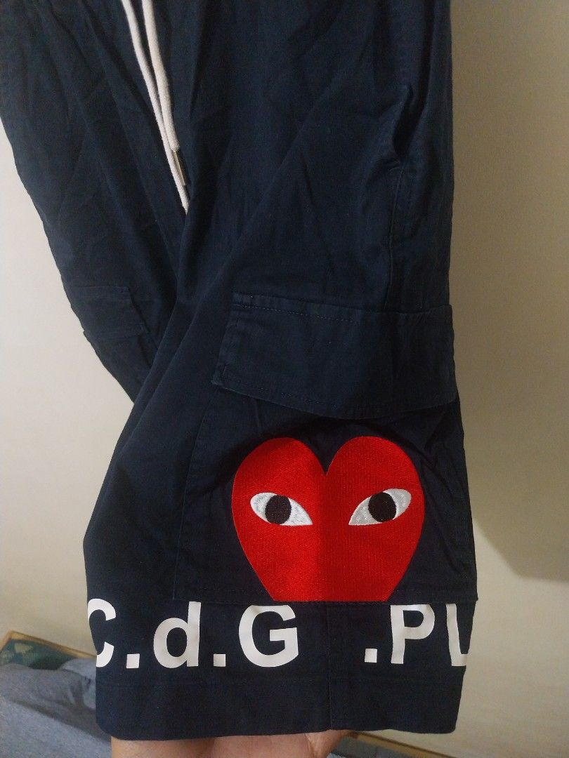 CDG Play Navy Shorts Size L (Category: Shorts) located in Davao. Submitted by thegraildept2026 (Listing ID 1467547895, Image 2). Description: - Brand: Comme des Garçons Play (CDG Play) - Color: Dark Navy Blue - Size: L (Fits true to size) - Details: Signature embroidered red heart patch with eyes, bold CDG lettering down the leg - Features: Elastic waistband, adjustable white drawstrings, and CDG-stamped metal aglets - Condition/Style: Casual str