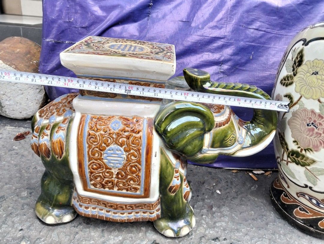 Ceramic Elephant Garden Stool Plant Stand (Category: Pots & Planters) located in Manila. Submitted by raymundm36884 (Listing ID 1467403116, Image 1). Description: - Unique Design: Glazed ceramic elephant shape with a vibrant orange, blue, and white patterned saddle. - Traditional Details: Flat square top featuring classic Asian motifs and a longevity symbol. - Dimensions: Roughly 17 inches tall and 18 inches from trunk to back leg. - Versatile Us
