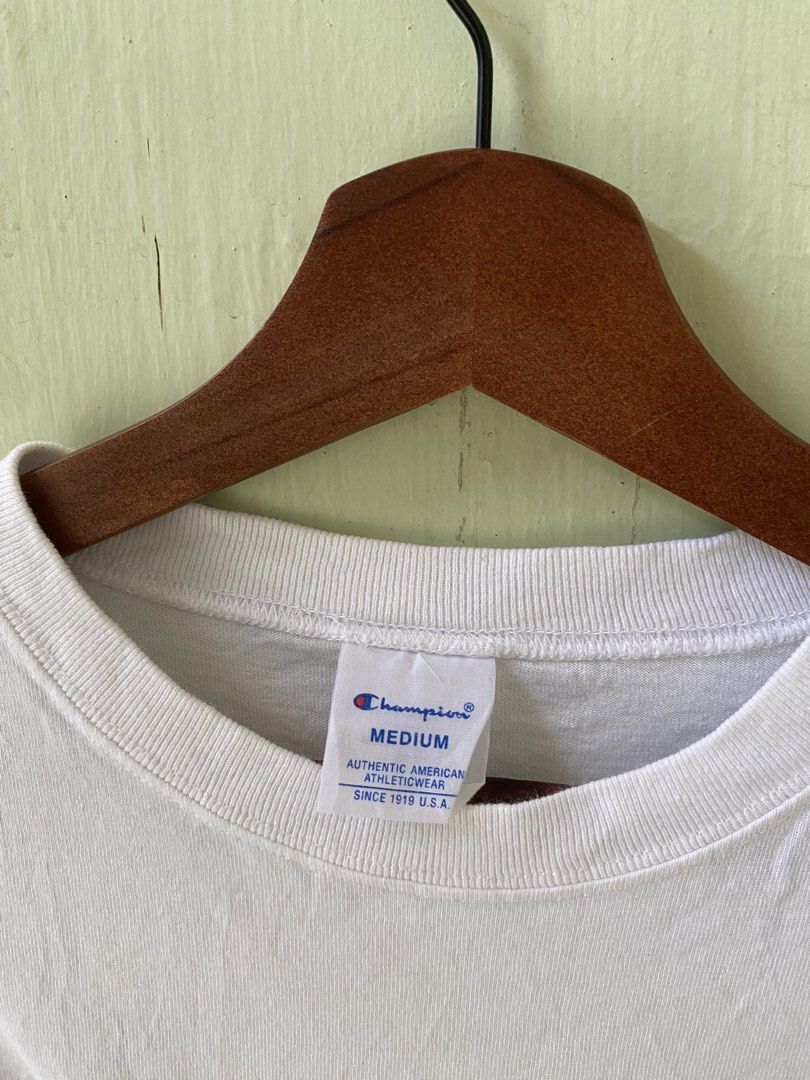 Champion C3-S301 White Script Logo T-Shirt Medium (Category: Tshirts & Polo Shirts ) located in Pandi. Submitted by nasya_thrift_collection2023 (Listing ID 1467413691, Image 2). Description: - Brand: Champion - Style: Script Logo T-Shirt - Color: White with black cursive chest logo - Size: Medium (Standard Fit) - Material: 100% Cotton (Made in China) - Details: Small embroidered Champion patch on left sleeve, crew neckline with inner branded labe