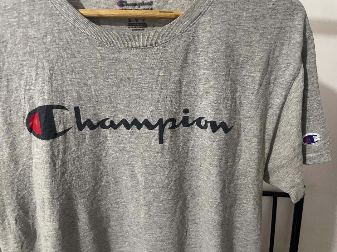 Champion Heather Grey Script Logo T-Shirt Medium (Category: Tshirts & Polo Shirts ) located in Manila. Submitted by mikeee03 (Listing ID 1467585765, Image 2). Description: - Brand: Champion - Color: Heather Grey - Size: Medium (tag on inner collar) - Design: Large script logo across chest with iconic embroidered C patch on left sleeve - Material: Soft, comfortable cotton blend - Origin: Made in El Salvador - Condition: Excellent, no stains or tea