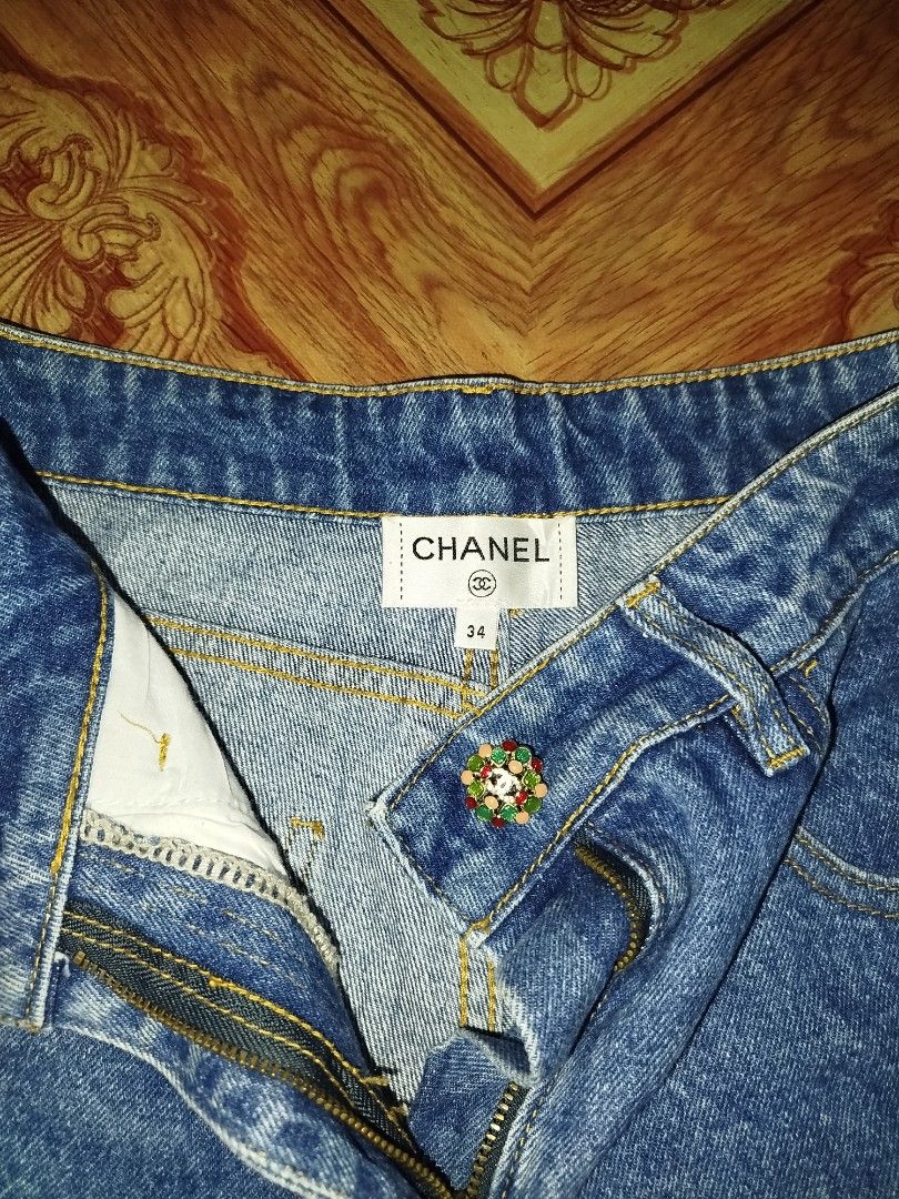 Chanel Denim Jeans Size 34 (Category: Jeans) located in Manila. Submitted by warrenwarr65028 (Listing ID 1467388417, Image 2). Description: - Brand: Chanel - Type: Blue denim jeans - Size: 34 (Made in Italy) - Fit: Structured fit with straight legs - Wash: Clean wash denim - Details: Decorative jeweled waist button, front patch pockets, and contrast yellow stitching - Condition: Excellent, with iconic brand and size labels inside the waistband.