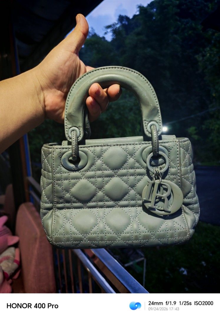 Christian Dior Lady Dior Mini Bag (Category: Luxury Bags & Wallets) located in Manila. Submitted by cleverwhale_45b7bc (Listing ID 1467375110, Image 1). Description: - Christian Dior mini handbag - Color: Light grey - Material: Quilted leather exterior - Interior: Red fabric with a zippered pocket - Embellishments: Iconic Dior charms - Condition: Shows some signs of wear on handles and corners, still beautiful..