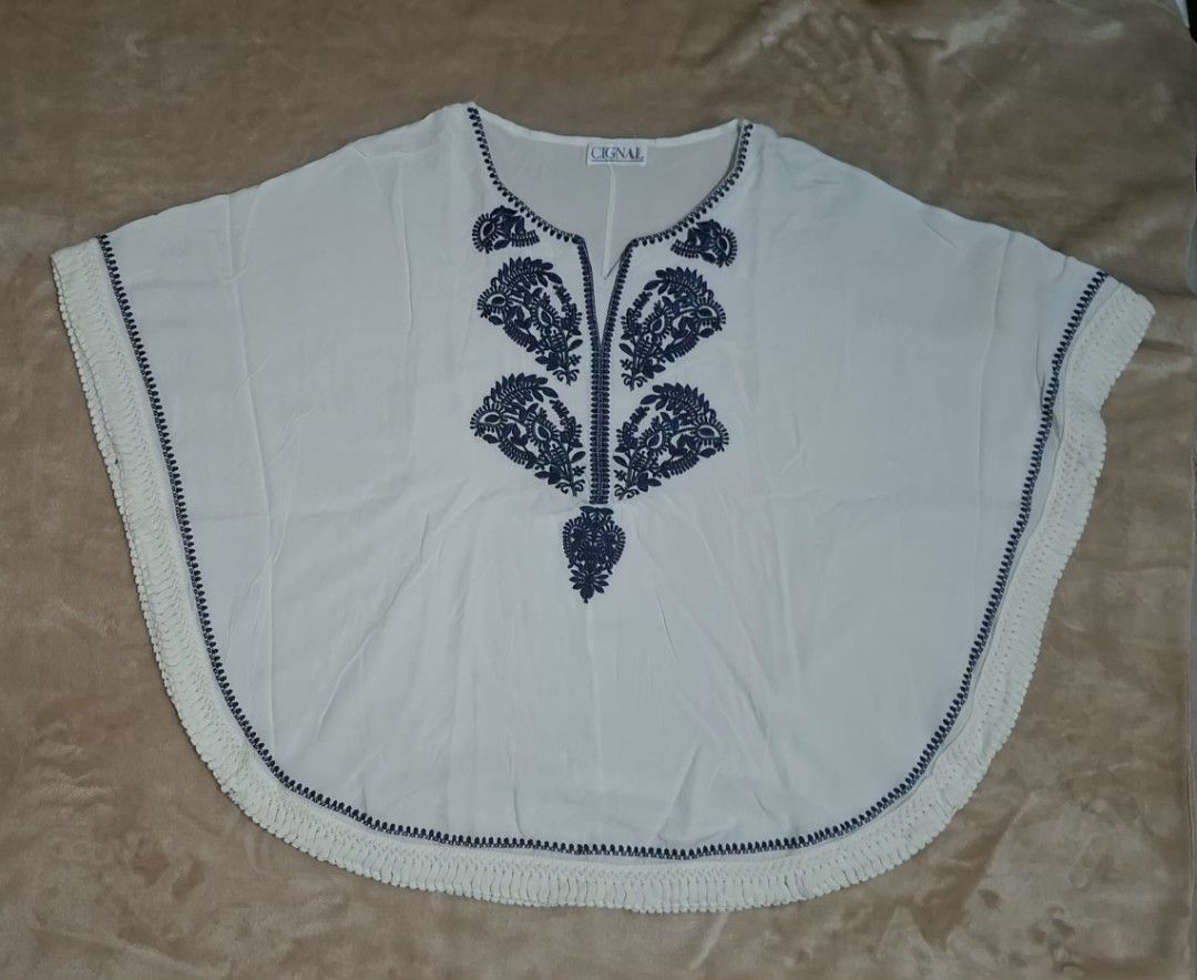 Cignal Embroidered Boho Poncho Kaftan Top (White/Navy) (Category: Blouses) located in Quezon City. Submitted by MP_Declutters (Listing ID 1467427305, Image 1). Description: Description: ✨ Cignal Resortwear Poncho Blouse ✨ Brand: Cignal Color: White base with deep navy blue floral embroidery Style: Relaxed poncho/kaftan silhouette with a flattering V-neck, wide draped wing sleeves, and a continuous lace crochet fringe trim lining the bottom hem Fi