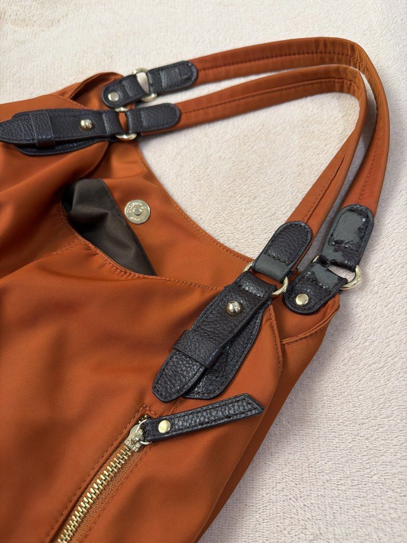 Closshi Orange Nylon Shoulder Bag (Category: Shoulder Bags) located in Zaragoza. Submitted by lerryparungao (Listing ID 1467375877, Image 3). Description: - Brand: Closshi - Color: Vibrant orange nylon with dark brown faux leather straps and trim - Pockets: Two vertical front zippered pockets and one inner zippered pocket - Interior: Lined with official Closshi brand tag - Features: Smooth zippers, sturdy shoulder straps, and a spacious design pe