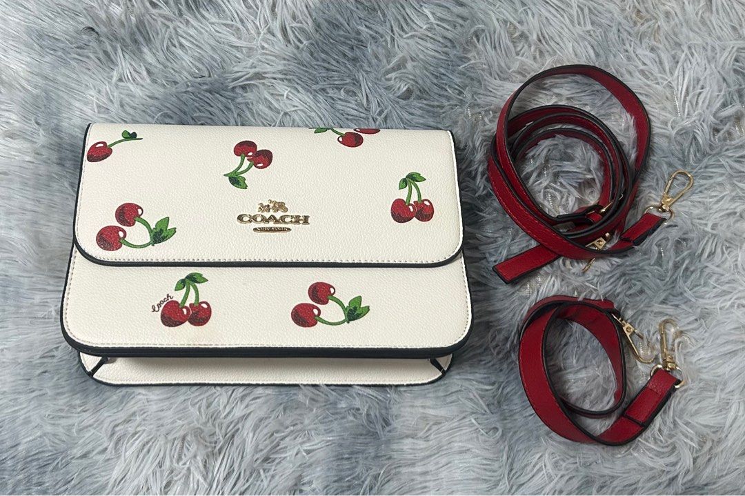 Coach Cherry Print Crossbody Bag (Category: Cross-body Bags) located in San Mateo. Submitted by pionaaa (Listing ID 1467390461, Image 1). Description: - Color: Cream/White with Red Cherry Print - Hardware: Gold-tone - Closure: Flap closure - Inclusions: Bag and strap [Add dust bag, box, receipt, or other inclusions if available.] - Class A RFS: Decluttering 📌 Slightly negotiable for sure buyers. 📦 Shipping fee shouldered by buyer..