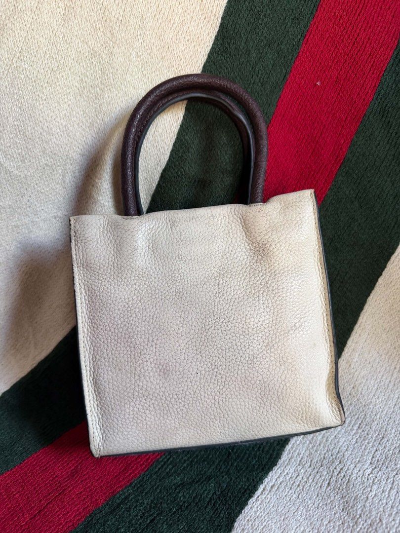 Coach Mini Tote Bag White Brown Leather (Category: Luxury Bags & Wallets) located in Bauang. Submitted by Fuzakenn (Listing ID 1467431941, Image 2). Description: - Brand: Coach - Style: Mini Tote / Crossbody - Color: Off-white pebble leather with dark brown handles - Hardware: Gold-tone - Interior: Brown fabric lining with creed patch (K2039-C2183) - Closure: Top flap with top handles - Inclusion: Matching adjustable leather crossbody strap - Con