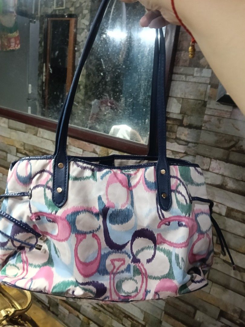 Coach Multi-color Print Tote Bag with Blue Straps (Category: Tote Bags) located in Quezon City. Submitted by bshoppe_ (Listing ID 1467486161, Image 2). Description: - Brand: Coach - Design: Colorful watercolor C-print pattern with dark blue leather handles and trim replace - Interior: Beige fabric lining with secure zipper pockets and slip compartments - Features: Drawstring details on the sides and metal protective feet on the bottom - Style: Ro