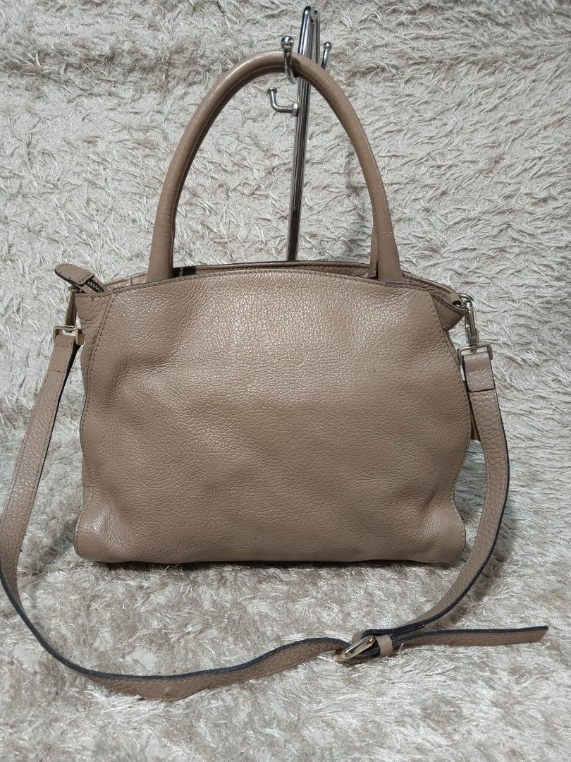 Coccinelle Beige Leather Tote Shoulder Bag (Category: Tote Bags) located in Caloocan City. Submitted by jezel07 (Listing ID 1467547351, Image 2). Description: - Brand: Coccinelle - Color: Classic beige with elegant gold hardware - Material: Genuine leather with normal signs of exterior wear - Straps: Dual top handles and a detachable, adjustable crossbody strap - Closure: Secure zip-top closure - Interior: Fabric-lined with practical slip pockets