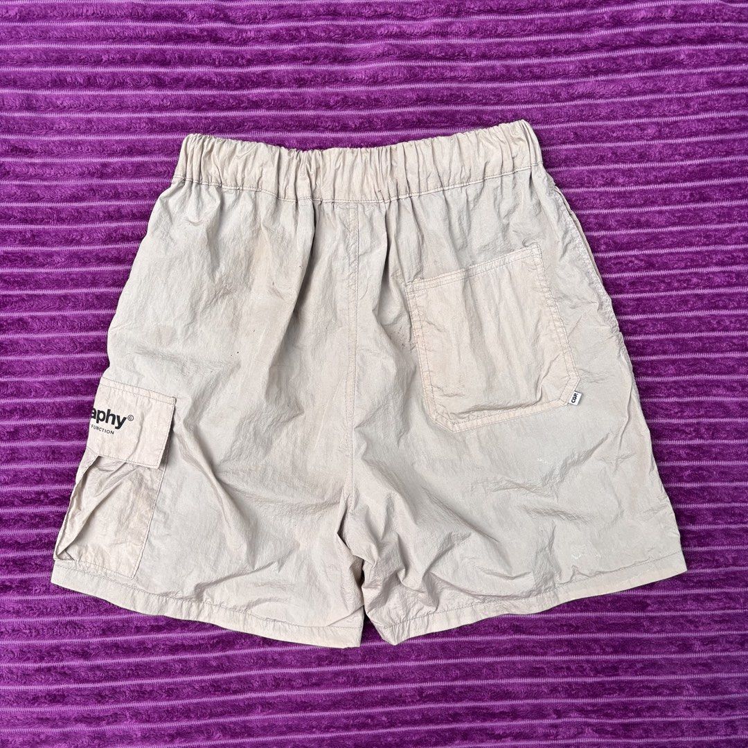 Codegraphy Utility Function Cargo Shorts Beige Size M (Category: Shorts) located in Manila. Submitted by loydgani (Listing ID 1467467358, Image 3). Description: - Brand: Codegraphy - Item: Utility Cargo Shorts - Color: Beige - Size: Medium (M) - Material: Lightweight nylon with interior black mesh lining - Waistband: Elastic with drawstring and black toggle - Pockets: Side cargo pocket with text branding and back pocket with CGP logo tag - Condit