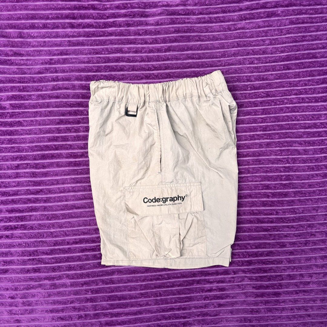 Codegraphy Utility Function Cargo Shorts Beige Size M (Category: Shorts) located in Manila. Submitted by loydgani (Listing ID 1467467358, Image 2). Description: - Brand: Codegraphy - Item: Utility Cargo Shorts - Color: Beige - Size: Medium (M) - Material: Lightweight nylon with interior black mesh lining - Waistband: Elastic with drawstring and black toggle - Pockets: Side cargo pocket with text branding and back pocket with CGP logo tag - Condit