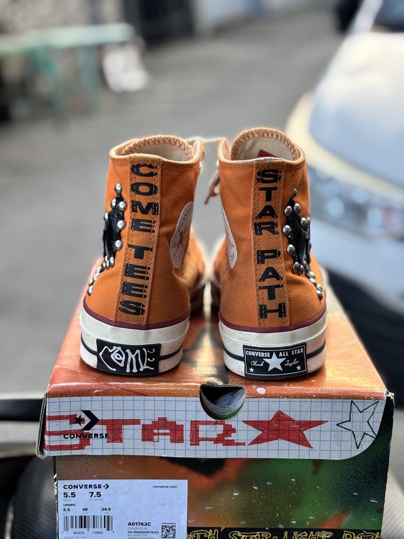 Converse Chuck Taylor x Come Tees High Top (Category: Sneakers) located in San Fernando. Submitted by kickslocker (Listing ID 1467378044, Image 3). Description: - Eye-catching orange canvas high tops with edgy black leather cutouts and metallic studs - Unique 'Come Tees' and 'Star Path' prints along the heels - Bold custom patterned black and white outsoles - Size: Men 5.5 / Women 7.5 (comfortably fits up to a Women 8.5) - Perfect for streetwear 
