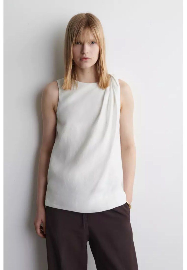 COS Twisted-Detail Linen Top (Category: Sleeveless) located in Taguig. Submitted by imgthrift (Listing ID 1467411967, Image 1). Description: Still availble in store for 5,500 - Brand: COS - Color: White - Size: EUR 36 / CN 160/84A - Material: Lightweight linen - Design: Sleeveless, round neckline, relaxed fit with unique twisted shoulder detail - Style: Clean, classic minimalist, perfect for pairing with trousers or skirts.