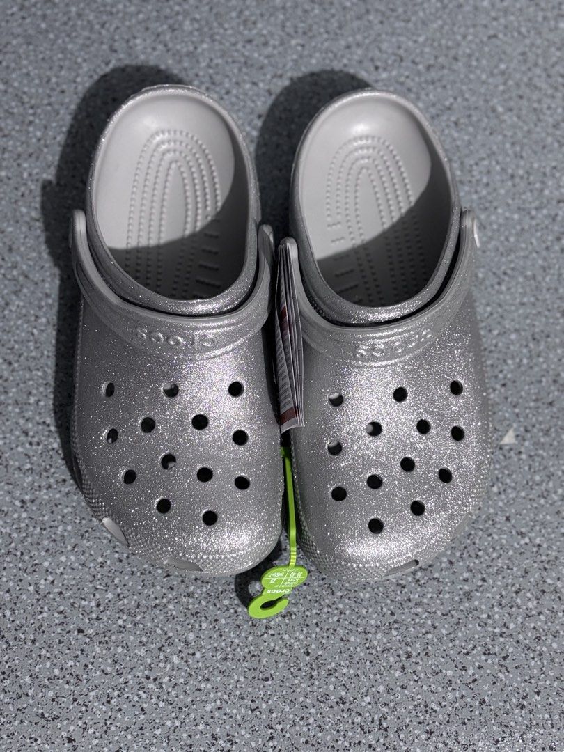 Crocs Classic Glitter Clog Silver Size M5/W7 (Category: Slippers and slides) located in Quezon City. Submitted by capableturtle_25 (Listing ID 1467480000, Image 2). Description: - Brand: Crocs Classic Clogs - Color/Finish: Silver Glitter - Condition: Brand new, unworn, with tags attached in original packaging - Material: Lightweight Croslite foam for all-day cushioning - Features: Ventilation ports for breathability, adjustable heel strap for ver