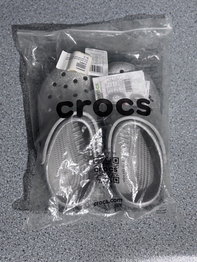 Crocs Classic Glitter Clog Silver Size M5/W7 (Category: Slippers and slides) located in Quezon City. Submitted by capableturtle_25 (Listing ID 1467480000, Image 1). Description: - Brand: Crocs Classic Clogs - Color/Finish: Silver Glitter - Condition: Brand new, unworn, with tags attached in original packaging - Material: Lightweight Croslite foam for all-day cushioning - Features: Ventilation ports for breathability, adjustable heel strap for ver