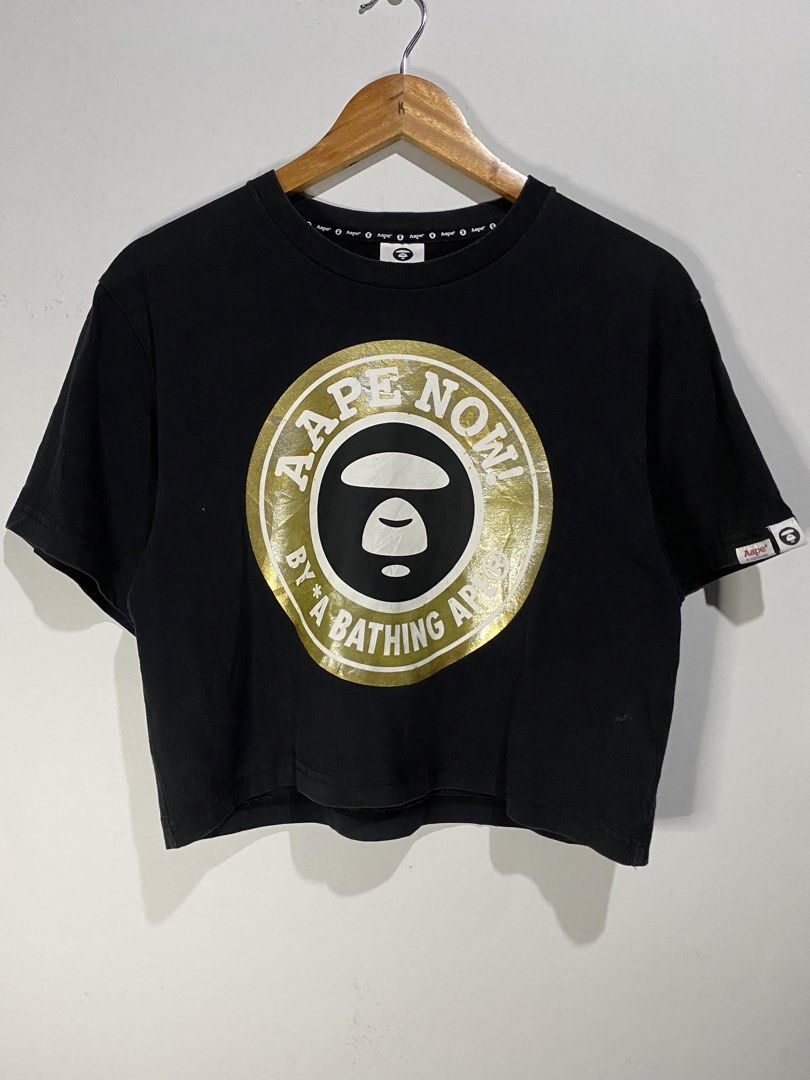 CROP AAPE SHIRT (Category: Others Tops) located in Jaen. Submitted by oshimamark58418 (Listing ID 1467536449, Image 1). Description: - Brand: Aape by A Bathing Ape - Style: Crop T-shirt / Streetwear top - Color: Black with gold and white graphic print ('Aape Now!') - Size: XXS (Measurements: 19x19 inches, fits like Small) - Features: Branded collar tape and sleeve logo tags - Condition: Good pre-owned condition.