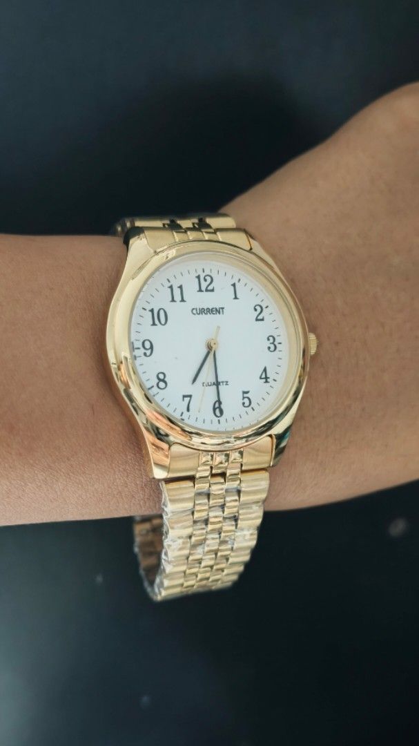 Current Gold Quartz Watch with White Dial (Category: Women's Watches) located in Taguig. Submitted by mercyeugen28914 (Listing ID 1467484295, Image 2). Description: - Brand: Current - Color: Shiny gold-tone - Dial: White round dial with bold, easy-to-read black numbers - Movement: Quartz movement with standard hands - Strap: Metal link bracelet with secure fold-over clasp - Condition: Brand new with protective plastic wrapping still intact on the