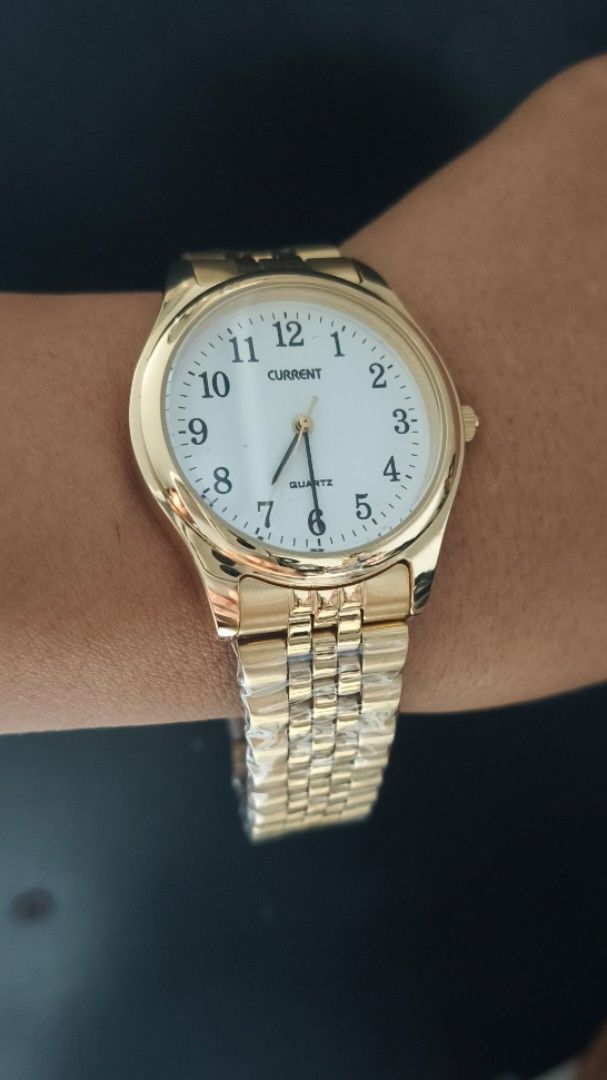 Current Gold Quartz Watch with White Dial (Category: Women's Watches) located in Taguig. Submitted by mercyeugen28914 (Listing ID 1467484295, Image 1). Description: - Brand: Current - Color: Shiny gold-tone - Dial: White round dial with bold, easy-to-read black numbers - Movement: Quartz movement with standard hands - Strap: Metal link bracelet with secure fold-over clasp - Condition: Brand new with protective plastic wrapping still intact on the