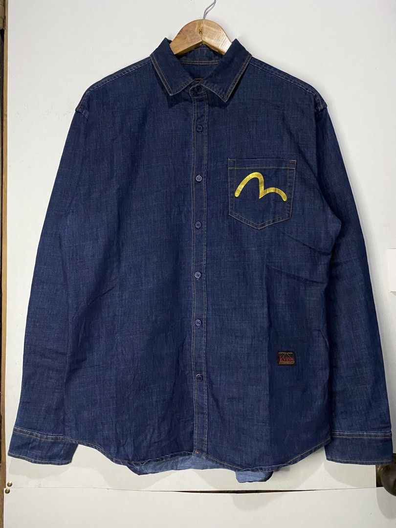 DENIM JACKET (Category: Coats, Jackets and Outerwear) located in Jaen. Submitted by oshimamark58418 (Listing ID 1467511417, Image 2). Description: - Brand: Evisu Heritage & Co. - Type: Denim Jacket / Button-up Shirt - Color: Dark Blue with Gold Print - Size: XL (Measured approx. 22" x 29") - Design: Large gold skull and typography graphic on the back, front chest pocket with gold seagull/gullwing logo, and custom Evisu branded buttons - Condition
