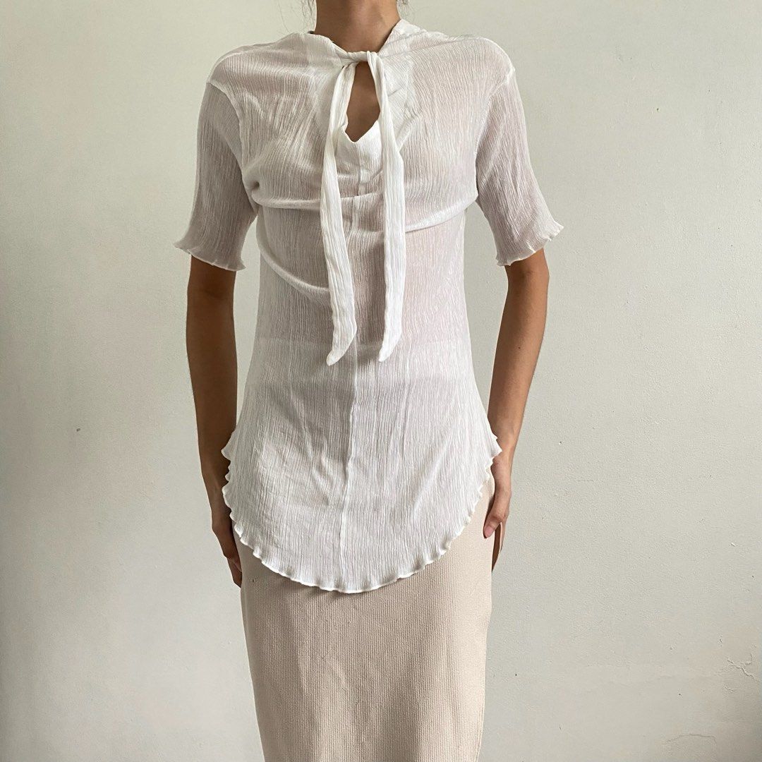 DOUBLE STEP White Tie-Front Crinkled Blouse (Category: Blouses) located in Tarlac. Submitted by luv__vintage (Listing ID 1467471260, Image 1). Description: - Brand: Double Step - Color: White - Style: Short sleeve blouse with tie neckline - Fabric: Lightweight, semi-sheer, textured crinkled material - Details: Rounded hem with lettuce edges at cuffs and bottom - Versatility: Easy to style casually with jeans or skirts.