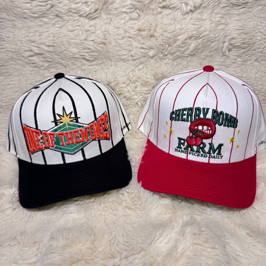 Field Grade Baseball Caps Pinstripe Snapbacks (Category: Caps & Hats) located in Manila. Submitted by westcity.mnl (Listing ID 1467512219, Image 1). Description: - Brand: Field Grade - Quantity: 2 snapback caps with pinstripe patterns - Cap 1 Details: Black brim with 'One Of Them Ones' embroidery - Cap 2 Details: Red brim with 'Cherry Bomb Farm' graphics, cherry patch at the back, and green underbrims - Size: Adjustable snap closure (fits most) -