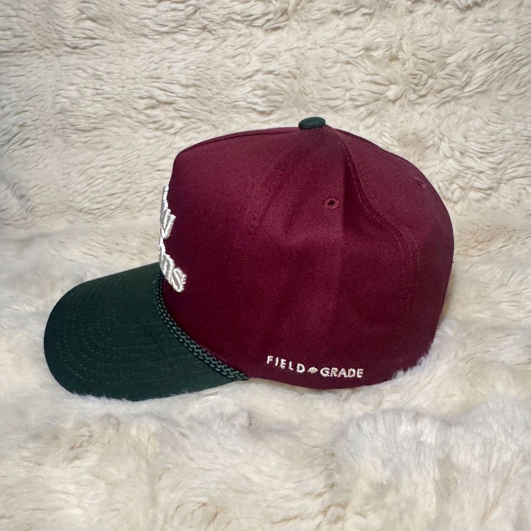 Field Grade By Any Means Maroon Green Snapback Hat (Category: Caps & Hats) located in Manila. Submitted by westcity.mnl (Listing ID 1467510543, Image 2). Description: - Brand: Field Grade - Design: Maroon crown with a contrasting green brim and white "By Any Means" cursive embroidery - Details: Classic braided rope across the front and stitched logo near the back - Fit: Adjustable snapback closure for a customized fit - Interior: Branded taping a