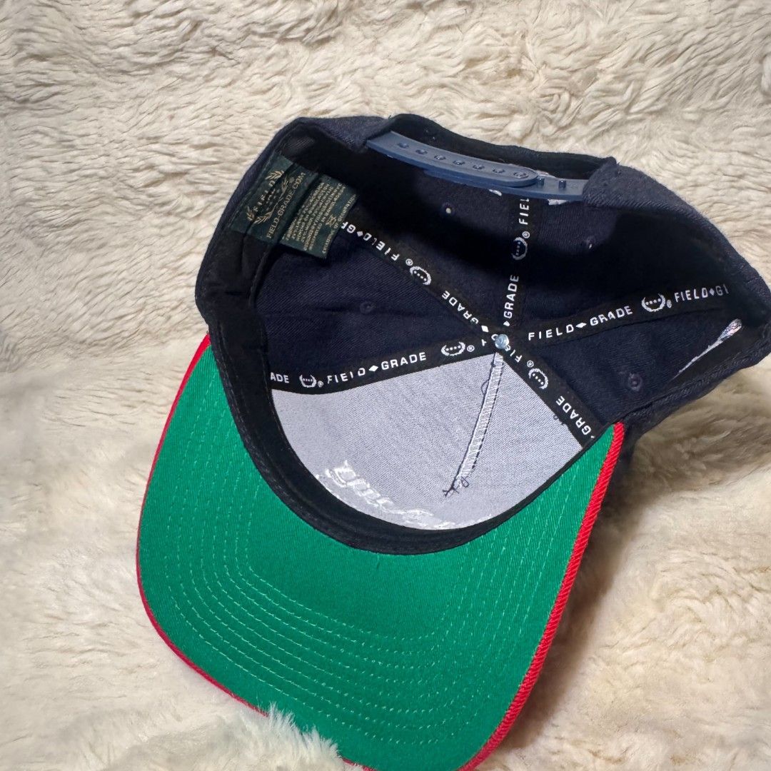 Field Grade By Any Means Snapback Hat (Category: Caps & Hats) located in Manila. Submitted by westcity.mnl (Listing ID 1467510897, Image 2). Description: - Brand: Field Grade - Design: Navy blue snapback with a bright red brim and green under brim - Front Embroidery: 'By Any Means' in white gothic font - Side Detail: Colorful embroidered 'Play the Field' logo patch - Fit: Adjustable plastic snap closure at the back - Interior: Clean lining with b