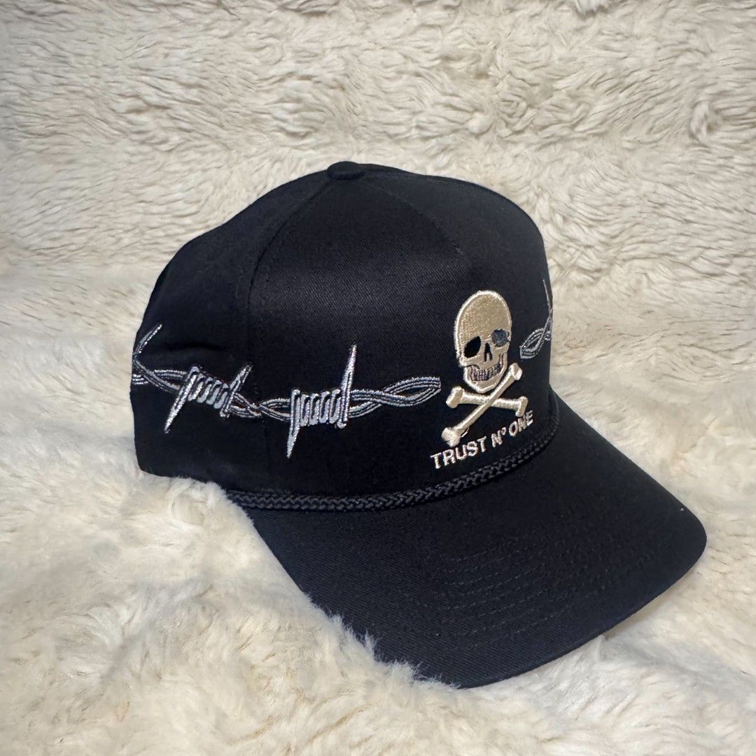 Field Grade Trust N One Skull Barbwire Hat (Category: Caps & Hats) located in Manila. Submitted by westcity.mnl (Listing ID 1467511262, Image 2). Description: - Brand: Field Grade - Item: Authentic Snapback Cap Collection - Design 1: Black hat with skull, crossbones, and barbed wire embroidery - Design 2: Blue, white, and black colorblock with lightning bolt panels - Branding: 'TRUST Nº ONE' embroidered on front and branded interior taped seams -