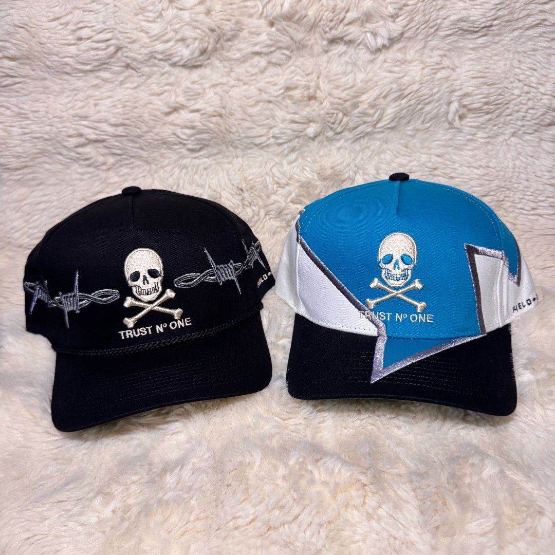 Field Grade Trust N One Skull Barbwire Hat (Category: Caps & Hats) located in Manila. Submitted by westcity.mnl (Listing ID 1467511262, Image 1). Description: - Brand: Field Grade - Item: Authentic Snapback Cap Collection - Design 1: Black hat with skull, crossbones, and barbed wire embroidery - Design 2: Blue, white, and black colorblock with lightning bolt panels - Branding: 'TRUST Nº ONE' embroidered on front and branded interior taped seams -
