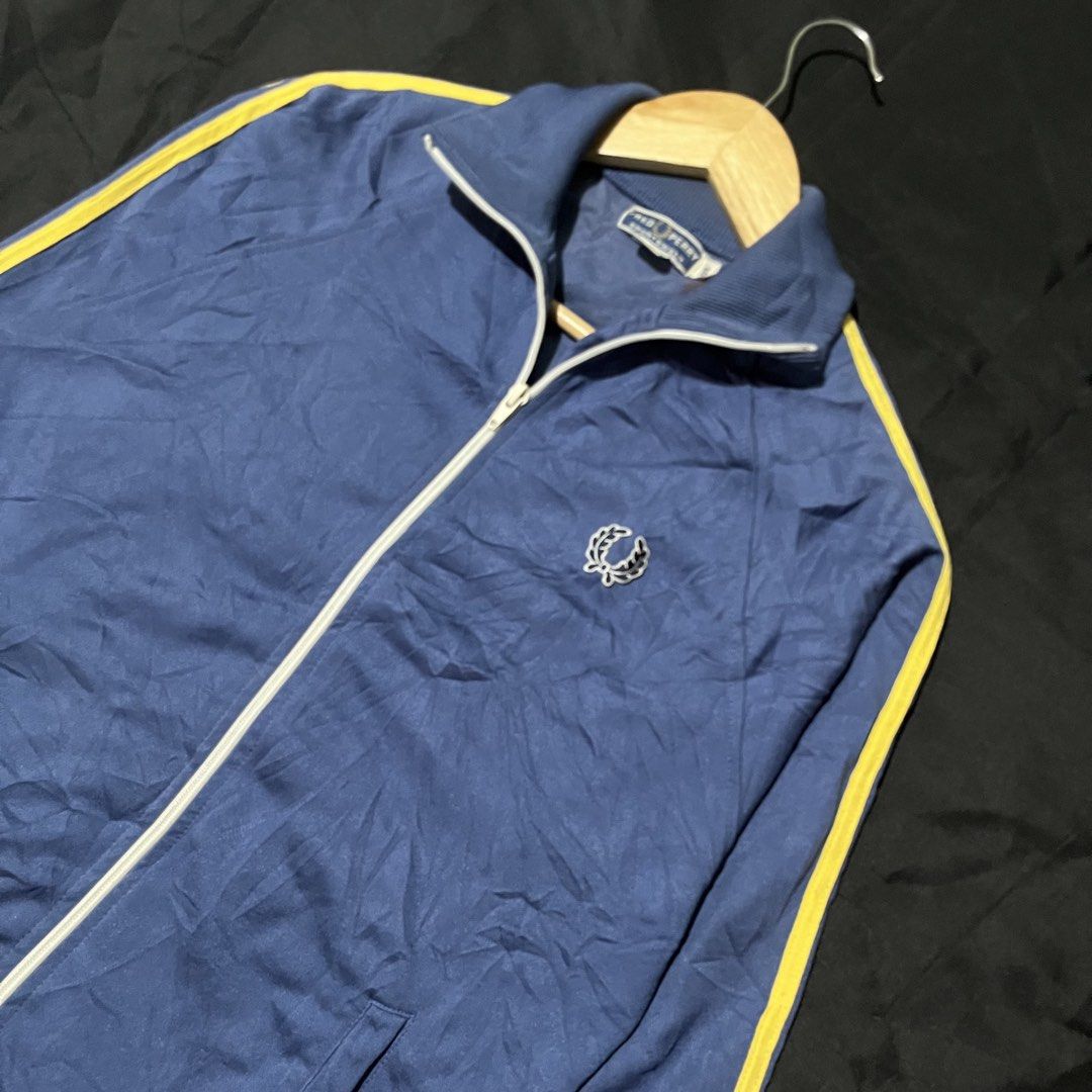 Fred Perry Track Jacket Blue Yellow Zip Up (Category: Coats, Jackets and Outerwear) located in Manila. Submitted by giormagne (Listing ID 1467472048, Image 2). Description: - Authentic blue Fred Perry track jacket with vintage sportswear vibe - Eye-catching yellow stripes down both sleeves - Full white zipper closure and matching white piping on the high collar - Signature embroidered laurel wreath logo on the left chest - Equipped with two funct