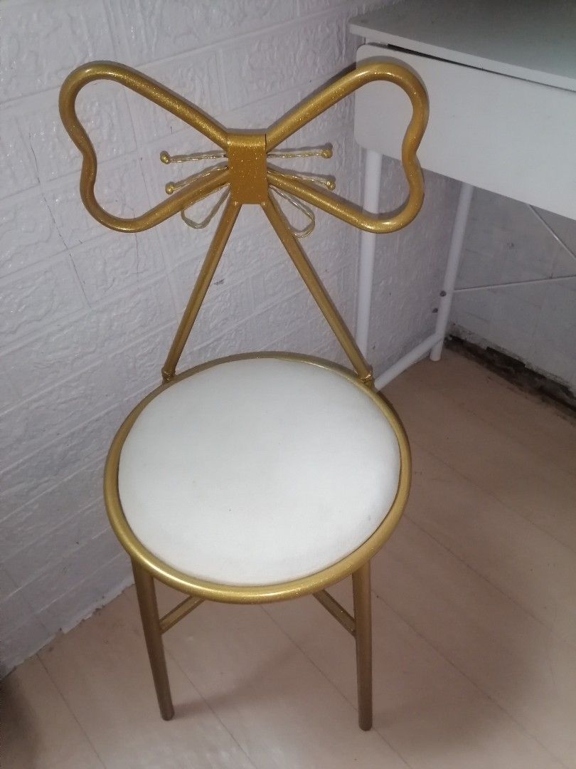Gold Bow Back Vanity Chair White Cushion (Category: Chairs) located in Manila. Submitted by yzekielshop (Listing ID 1467390688, Image 1). Description: - Gold metal frame with a gorgeous glitter finish - Unique bow-shaped backrest with wire knot details - Comfortable round seat with white upholstery - Sleek and sturdy slim cylindrical legs - Compact size, ideal for makeup desks and vanity spaces.
